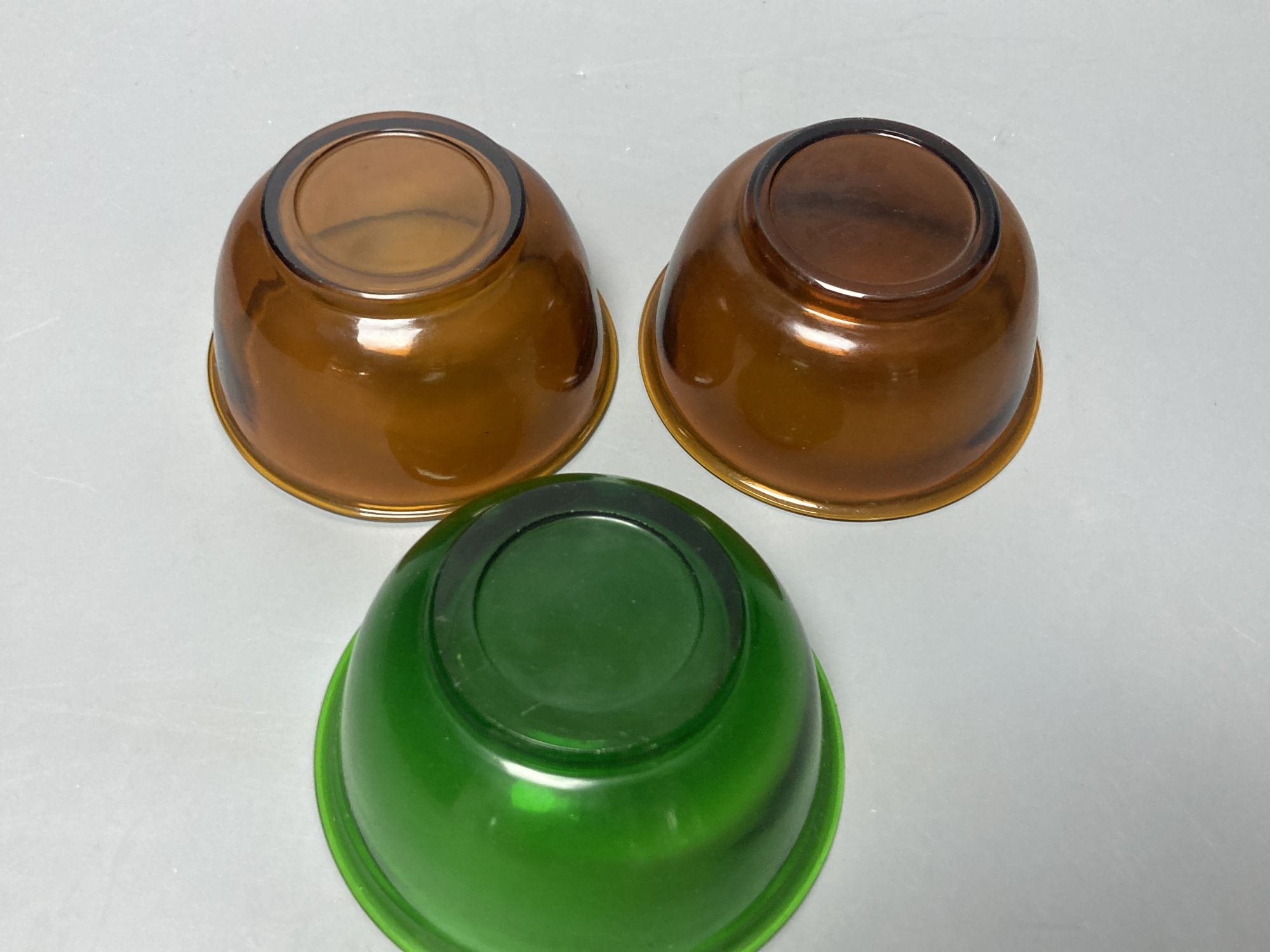 A pair of Chinese Beijing amber glass bowls, together with a similar green glass bowl, diameter 11cm